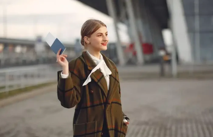 A traveler holding passport and travel documents near an airport terminal — after Portugal student visa AIMA residence permit
