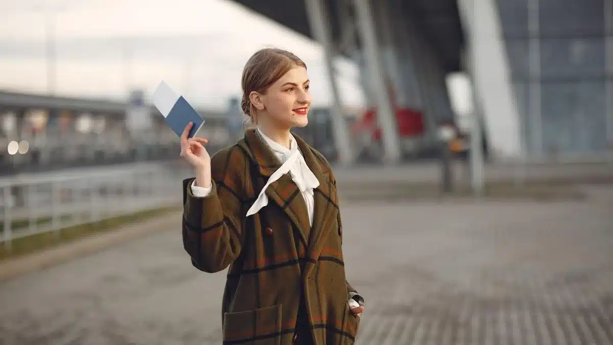 A traveler holding passport and travel documents near an airport terminal — after Portugal student visa AIMA residence permit