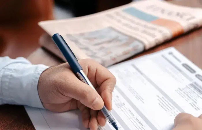 A person completing official-looking paperwork at a desk — Portugal student residence permit renewal