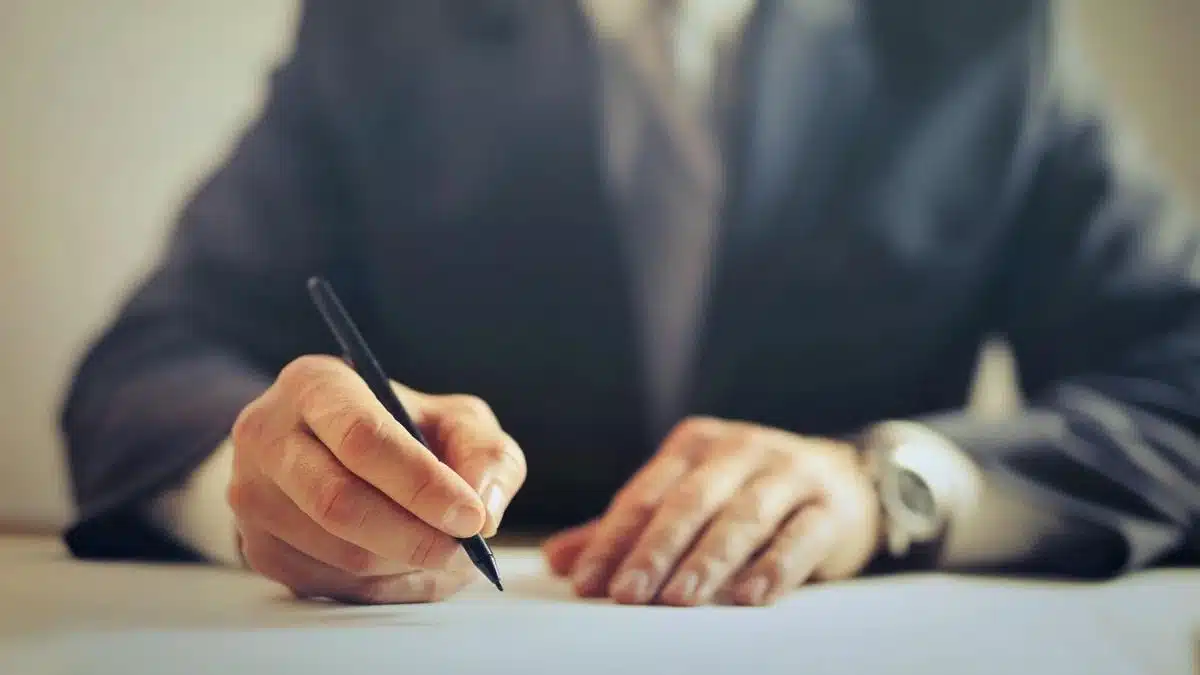 A businessman signing a formal contract at an office desk — Portugal Startup Visa company before applying