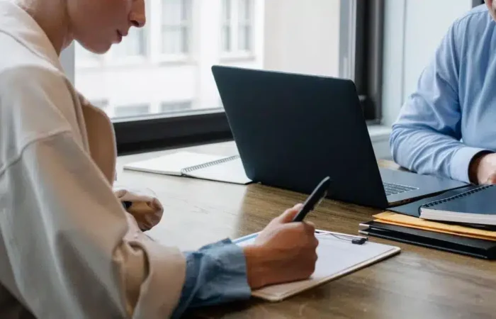 Two professionals reviewing and signing documents beside a laptop — Portugal Startup Visa application process