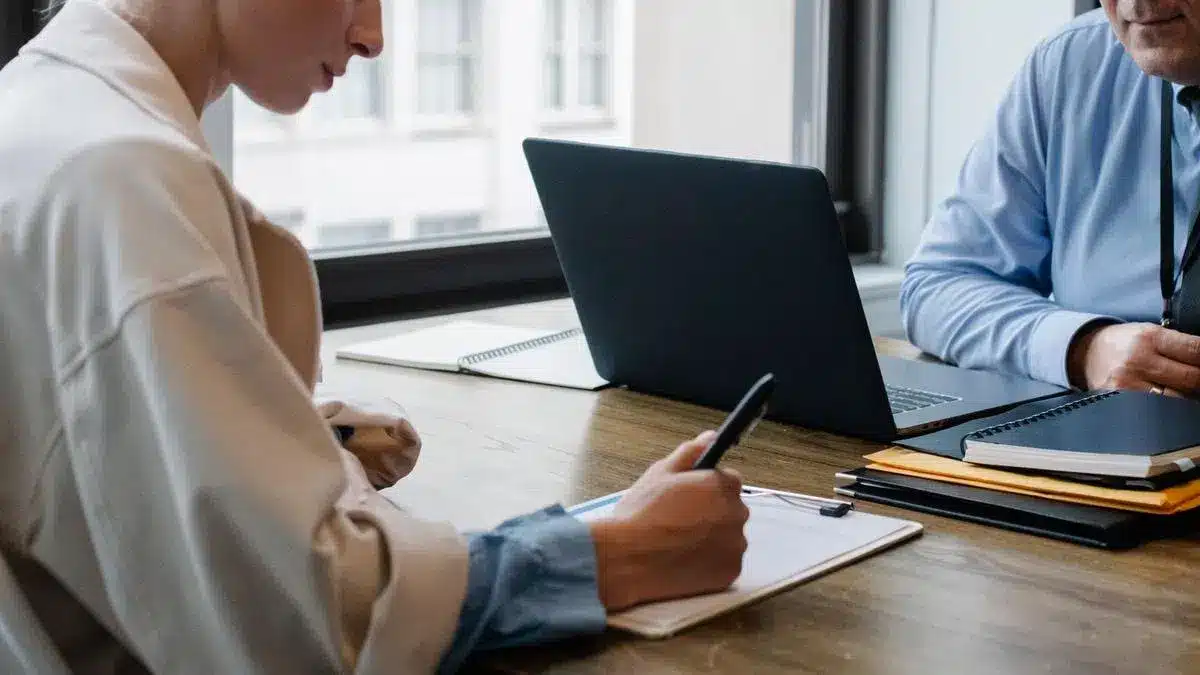 Two professionals reviewing and signing documents beside a laptop — Portugal Startup Visa application process