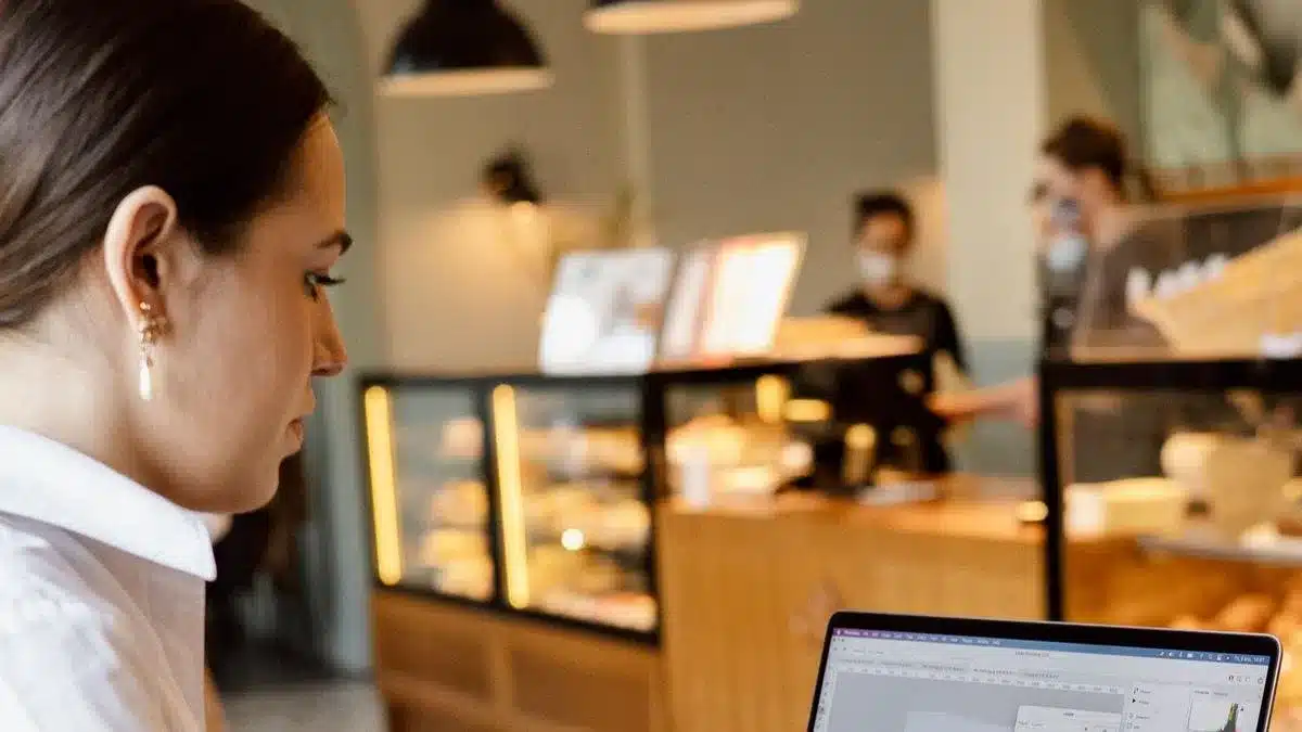 A remote worker using a laptop in a modern coffee shop — Portugal digital nomad temporary stay vs residence visa
