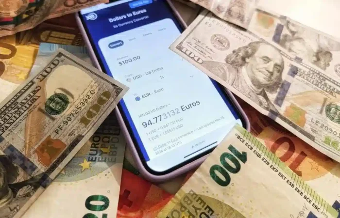Euro and US dollar banknotes around a smartphone displaying a currency converter — Portugal digital nomad visa income foreign currency