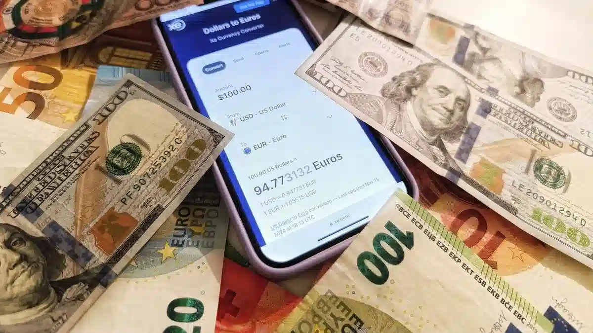 Euro and US dollar banknotes around a smartphone displaying a currency converter — Portugal digital nomad visa income foreign currency