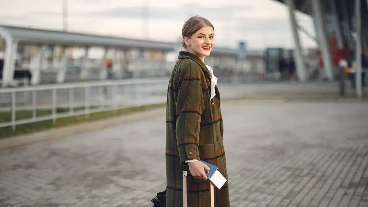 A traveler walking with luggage and a passport at a transportation terminal — after Portugal digital nomad visa AIMA residence permit