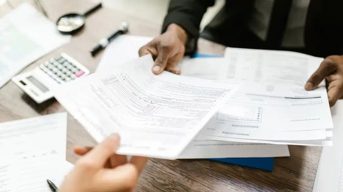 Two professionals exchanging official paperwork across an office desk — how to get NISS Portugal foreigner